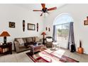 Bright living room featuring a ceiling fan, tile flooring, and a large arched window at 8429 W Vernon Ave, Phoenix, AZ 85037