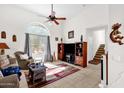 Living room with a ceiling fan, arched window, tile flooring, and staircase access at 8429 W Vernon Ave, Phoenix, AZ 85037
