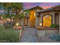 Charming front entrance with a brick walkway, stucco walls, manicured landscaping, and hanging lamps at 9 E Los Arboles Cir, Tempe, AZ 85284
