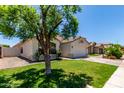 The exterior of the home features a well-maintained lawn and desert landscaping, with shade from mature tree at 12821 W Holly St, Avondale, AZ 85392