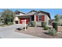 Attractive home with a well-maintained front yard, desert landscaping, and a bright red garage door at 13487 W Buckskin Trl, Peoria, AZ 85383