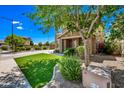 Close-up of charming home exterior showing stone porch, manicured lawn, bushes, and a welcoming entrance at 18045 W Rimrock St, Surprise, AZ 85388