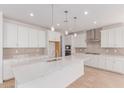 Bright kitchen featuring a large quartz island, stainless appliances, and stylish pendant lighting at 20262 W Monterey Way, Buckeye, AZ 85396