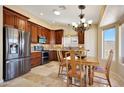 Well-lit kitchen with dark wood cabinets, stainless steel appliances, and a dining area at 20739 N 106Th Ave, Peoria, AZ 85382