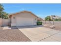 Side view of a single-story home with a desert-style yard, featuring a two-car garage and a well-kept lawn at 23638 N 41St Ave, Glendale, AZ 85310