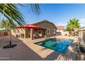 Backyard featuring a sparkling pool, covered patio, and lush landscaping at 13153 W Cottontail Ln, Peoria, AZ 85383