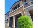 Townhome's stylish exterior with stone facade, covered entrance, and vibrant landscaping at 2323 E Huntington Dr, Phoenix, AZ 85040