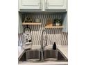 Close-up view of the kitchen sink area with decor, floating shelves, and stylish backsplash at 286 W Palomino Dr # 78, Chandler, AZ 85225