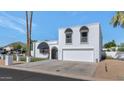 Stunning white home featuring black awnings, desert landscaping, and a paved driveway with a two-car garage at 34 E Boca Raton Rd, Phoenix, AZ 85022