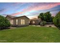 Backyard features a spacious lawn, outdoor seating under a pergola, and a built-in grill at 4318 N 180Th Dr, Goodyear, AZ 85395