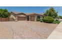 View of the exterior featuring a three-car garage and brick driveway with beautifully maintained front yard at 4318 N 180Th Dr, Goodyear, AZ 85395