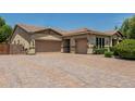 Exterior shot showcasing the three-car garage and extended brick driveway and landscaped front yard at 4318 N 180Th Dr, Goodyear, AZ 85395