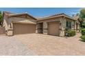 Exterior shot of the home's three-car garage with neutral paint and wide brick driveway at 4318 N 180Th Dr, Goodyear, AZ 85395