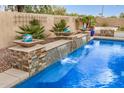 Beautiful pool area featuring rock waterfall features and lush landscaping in a private backyard setting at 4453 S Huachuca Way, Chandler, AZ 85249
