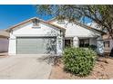 Charming single-story home featuring a gray two-car garage and a well-maintained front yard with mature landscaping at 513 S 115Th Dr, Avondale, AZ 85323