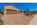 Spacious driveway with brick pavers leading to a three-car garage, surrounded by desert landscaping at 16704 W Oracle Rim Dr, Surprise, AZ 85387