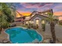 Inviting backyard features a sparkling pool, desert landscaping, and patio area under a beautiful sky at sunset at 20507 W Daniel Pl, Buckeye, AZ 85396