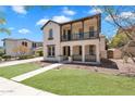 Stunning two-story home with a covered porch, balcony, landscaped lawn, and inviting walkway under blue skies at 20507 W Daniel Pl, Buckeye, AZ 85396