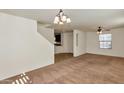 Large living room featuring neutral colored carpet, staircase, view to kitchen, and modern ceiling fan at 3535 E Erie St, Gilbert, AZ 85295