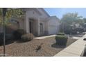 Inviting one-story home with desert landscaping, a two-car garage, and an arched entryway to the front door at 43634 W Roth Rd, Maricopa, AZ 85138