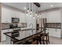 Modern kitchen with stainless steel appliances, white cabinetry, and a large island with a black countertop at 5659 N 195Th Dr, Litchfield Park, AZ 85340