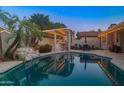 Backyard pool with lights and a covered bar area, perfect for outdoor entertaining in the evening at 6715 S Lakeshore Dr, Tempe, AZ 85283