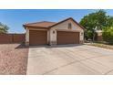 View of the house with a terracotta roof, neutral stucco, and a spacious three-car garage at 1443 N Poppy St, Casa Grande, AZ 85122