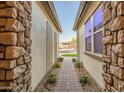 Inviting entranceway featuring a brick path, decorative trellises, and stone wall accents at 15803 W Almeria Rd, Goodyear, AZ 85395