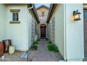 Charming entryway with a brick pathway, decorative trellises, and a classic wooden front door at 15803 W Almeria Rd, Goodyear, AZ 85395