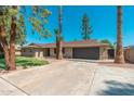 Home exterior featuring manicured lawn, desert landscaping, and convenient driveway to a attached garage at 1810 W Orchid Ln, Phoenix, AZ 85021