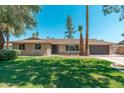 Attractive single-story home with well-maintained lawn, charming brick accents, and an attached two-car garage at 1810 W Orchid Ln, Phoenix, AZ 85021