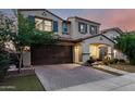 Beautiful two-story house with a brick driveway, manicured lawn, and a charming front porch with outdoor seating at 20576 W Briarwood Dr, Buckeye, AZ 85396
