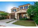 Two-story home boasts a brick driveway, green lawn, and a welcoming front porch with outdoor seating and colorful plants at 20576 W Briarwood Dr, Buckeye, AZ 85396