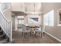 A virtual staged dining room with a round table, four chairs, tile floors, a large window, and a modern chandelier at 2116 W Fawn Dr, Phoenix, AZ 85041
