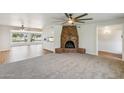 Spacious living room with a cozy brick fireplace, a ceiling fan, an open layout, and an adjacent room with lots of natural light at 2847 S Bala Dr, Tempe, AZ 85282