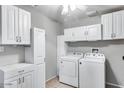 Functional laundry room with ample cabinet space, modern washer, and dryer for convenient chores at 3102 W Betty Elyse Ln, Phoenix, AZ 85053