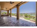Spacious covered patio with stone flooring, built-in grill, ceiling fans and a stunning view of the lush landscaping and golf course at 36172 N Secret Garden Path, Queen Creek, AZ 85140