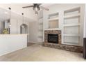 Bright living room with stone fireplace, built-in shelving, and adjacent breakfast bar at 11724 N 148Th Ave, Surprise, AZ 85379