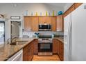Kitchen featuring wood cabinets, granite countertops, stainless steel appliances and wood flooring at 14300 W Bell Rd # 312, Surprise, AZ 85374