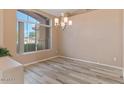 Dining area featuring a modern chandelier, wood-look floors and a large window for natural light at 15032 N 54Th Pl, Scottsdale, AZ 85254