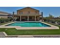 A backyard featuring a refreshing pool, well-manicured artificial turf, and a covered balcony at 1932 S 220Th Dr, Buckeye, AZ 85326