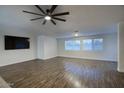 Spacious living room featuring wood-look flooring, large windows, and a modern ceiling fan at 19906 N 76Th Ave, Glendale, AZ 85308