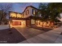 Two-story home showcasing a garage with stone accents and a balcony, beautifully lit up at dusk at 20689 W Valley View Dr, Buckeye, AZ 85396