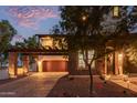 Two-story home featuring stone accents, a balcony situated over the garage, and meticulous landscaping at twilight at 20689 W Valley View Dr, Buckeye, AZ 85396