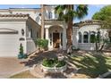 Elegant home exterior featuring a lush garden, mature palm trees, and a circular driveway at 2135 E Clipper Ln, Gilbert, AZ 85234