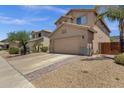 A tan two-story home features a two-car garage and a brick paver driveway border with desert landscaping at 25409 N 40Th Ln, Phoenix, AZ 85083