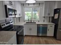 Modern kitchen with stainless steel appliances, white cabinetry, and a sink beneath a window at 3104 E Broadway Rd # 207, Mesa, AZ 85204