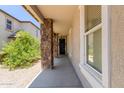 Covered entryway featuring stone pillars, leading to a black front door with decorative wreath, enhancing curb appeal at 3692 N 292Nd Dr, Buckeye, AZ 85396