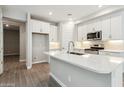 Bright kitchen with white cabinets, center island with stone countertops, wood floors and stainless steel appliances at 5815 E Covey Ln, Phoenix, AZ 85054