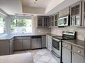 Well-lit kitchen featuring gray cabinets, stainless steel appliances, and a view from the sink window at 7770 E Camelback Rd # 23, Scottsdale, AZ 85251
